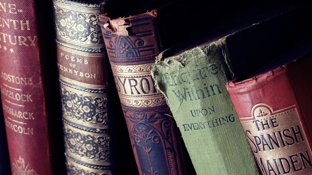 Close-up of vintage leather-bound books with ornate designs on a bookshelf.
