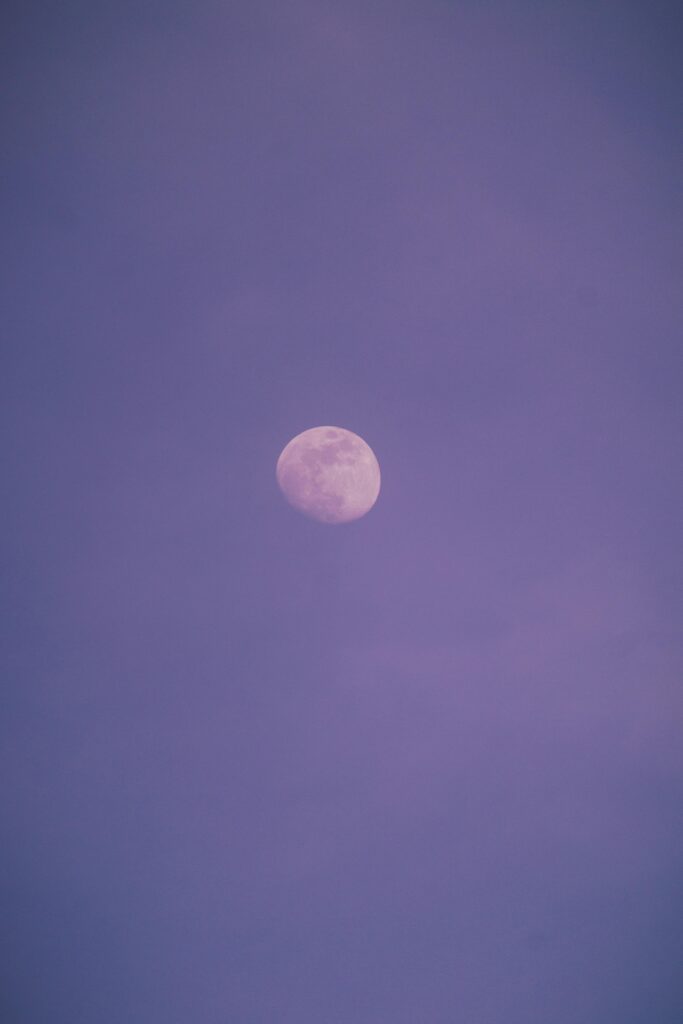 Serene view of the moon against a light purple twilight sky, offering a tranquil and magical scene.